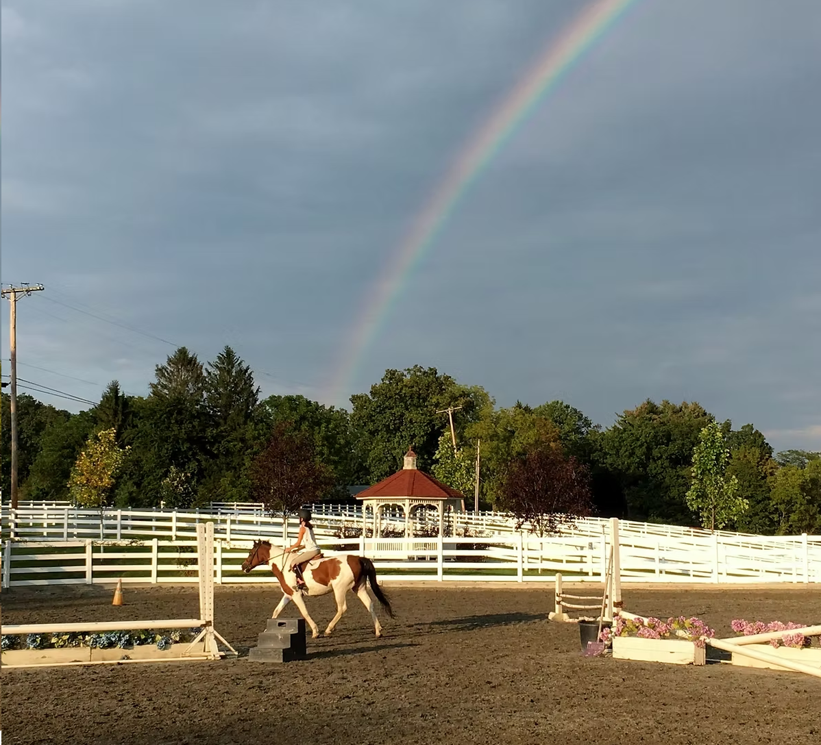 A lesson in the outdoor ring under a rainbow